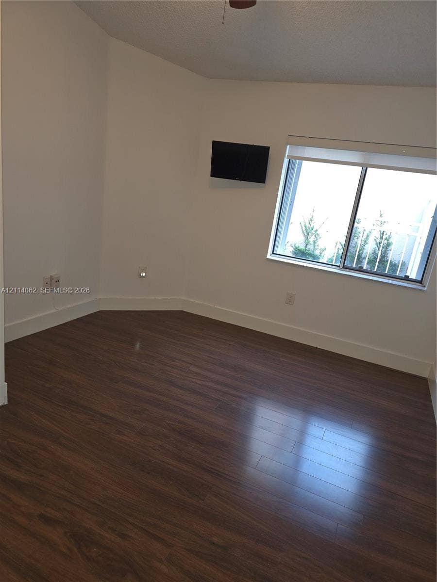 Weston, Weston, FL 33326 Room featuring wood-finish flooring, white walls, and a sliding window with installed roller shade
