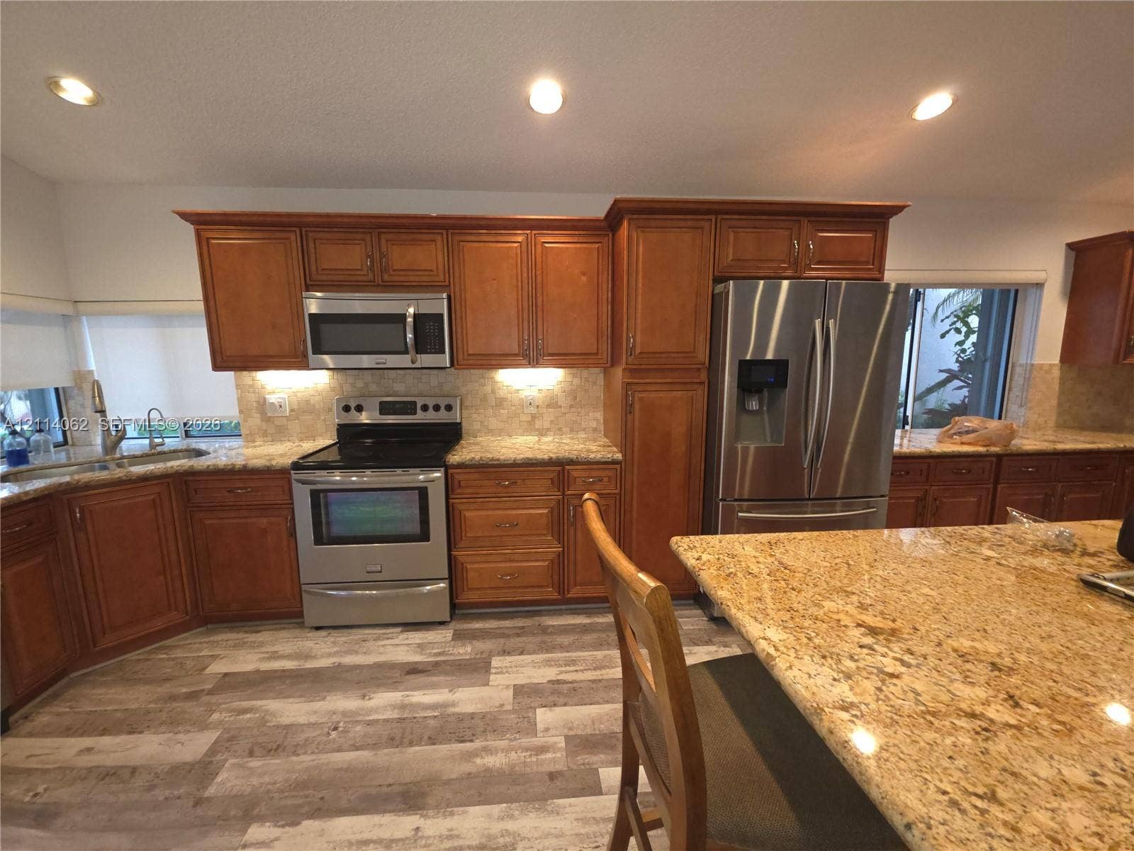 Weston, Weston, FL 33326 Kitchen featuring wood cabinetry, stainless steel appliances, patterned stone countertops, wood-finish flooring, and recessed ceiling lighting