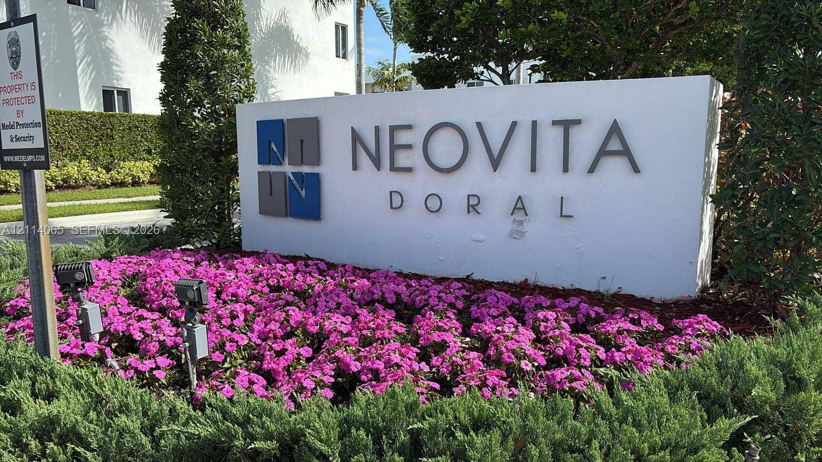 Monument sign with dimensional lettering featuring curated landscaping, floral plantings, and integrated spotlight fixtures
