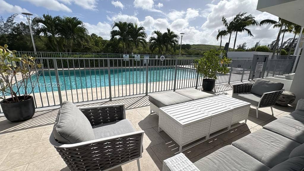 Outdoor terrace featuring stone-finish tiling, metal safety fencing, and a swimming pool