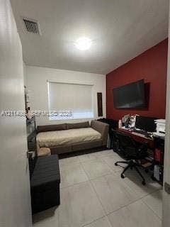 Room featuring large-format ceramic tile flooring, a prominent accent wall, and a window equipped with an integrated roller shade