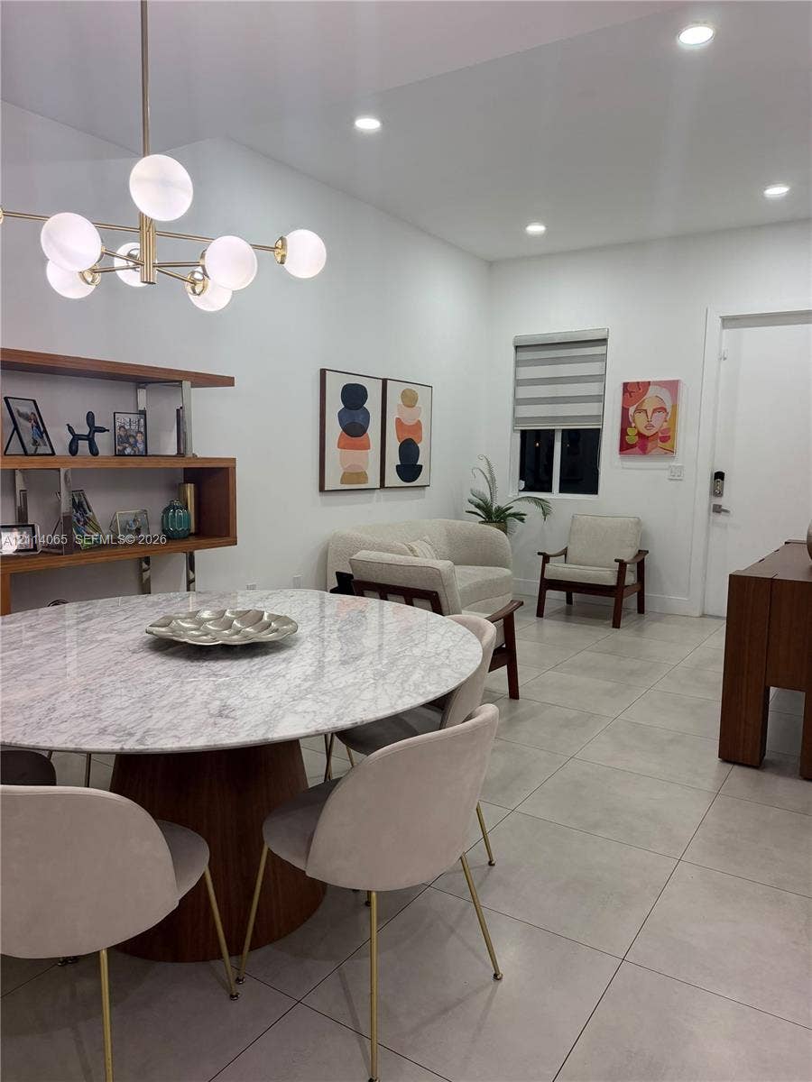 Large-format light-toned tile flooring, multi-globe chandelier with brass-finish hardware, and built-in wood shelving unit