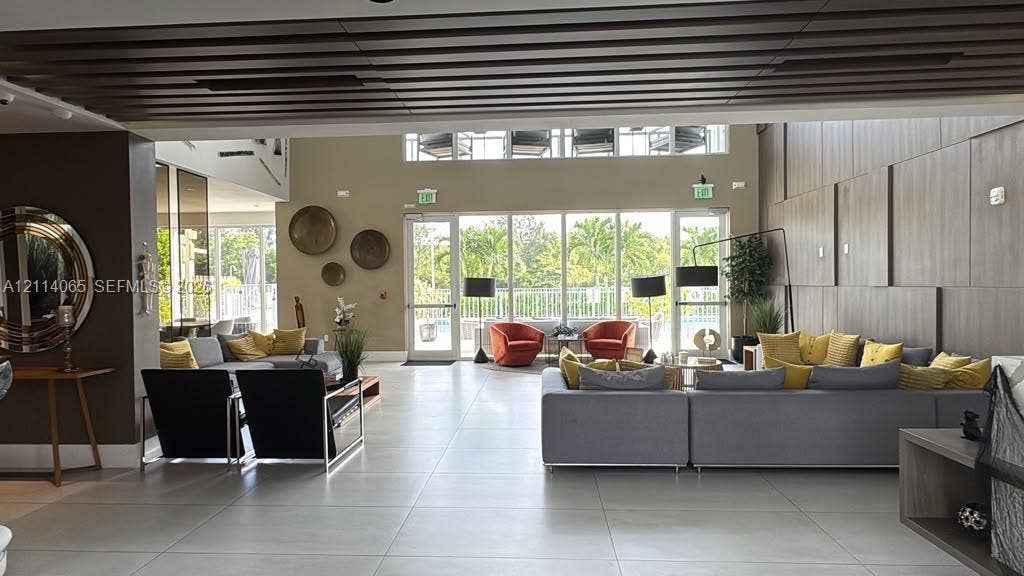 Open-concept interior featuring large-format tile flooring, slatted wood-finish ceiling detailing, expansive floor-to-ceiling glass windows, and vertical wood-panel wall cladding