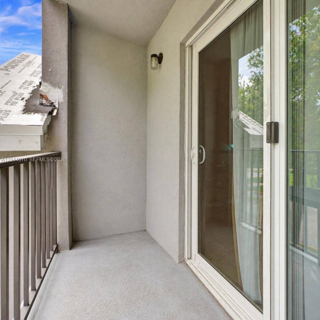 15400 SW 284th Street, #1204, Homestead, Homestead, FL 33033 Private balcony featuring a concrete floor, metal railing, exterior wall-mounted light fixture, and double-pane sliding glass door