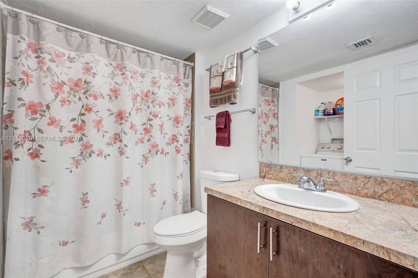 15400 SW 284th Street, #1204, Homestead, Homestead, FL 33033 Bathroom vanity featuring a stone-patterned countertop, oval drop-in sink, and dark wood-finish cabinetry, complemented by a large wall-mounted mirror and a built-in laundry closet