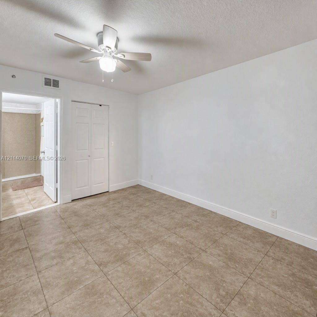 15400 SW 284th Street, #1204, Homestead, Homestead, FL 33033 Interior space featuring large-format ceramic tile flooring, a multi-blade ceiling fan with integrated lighting, and a bi-fold closet door