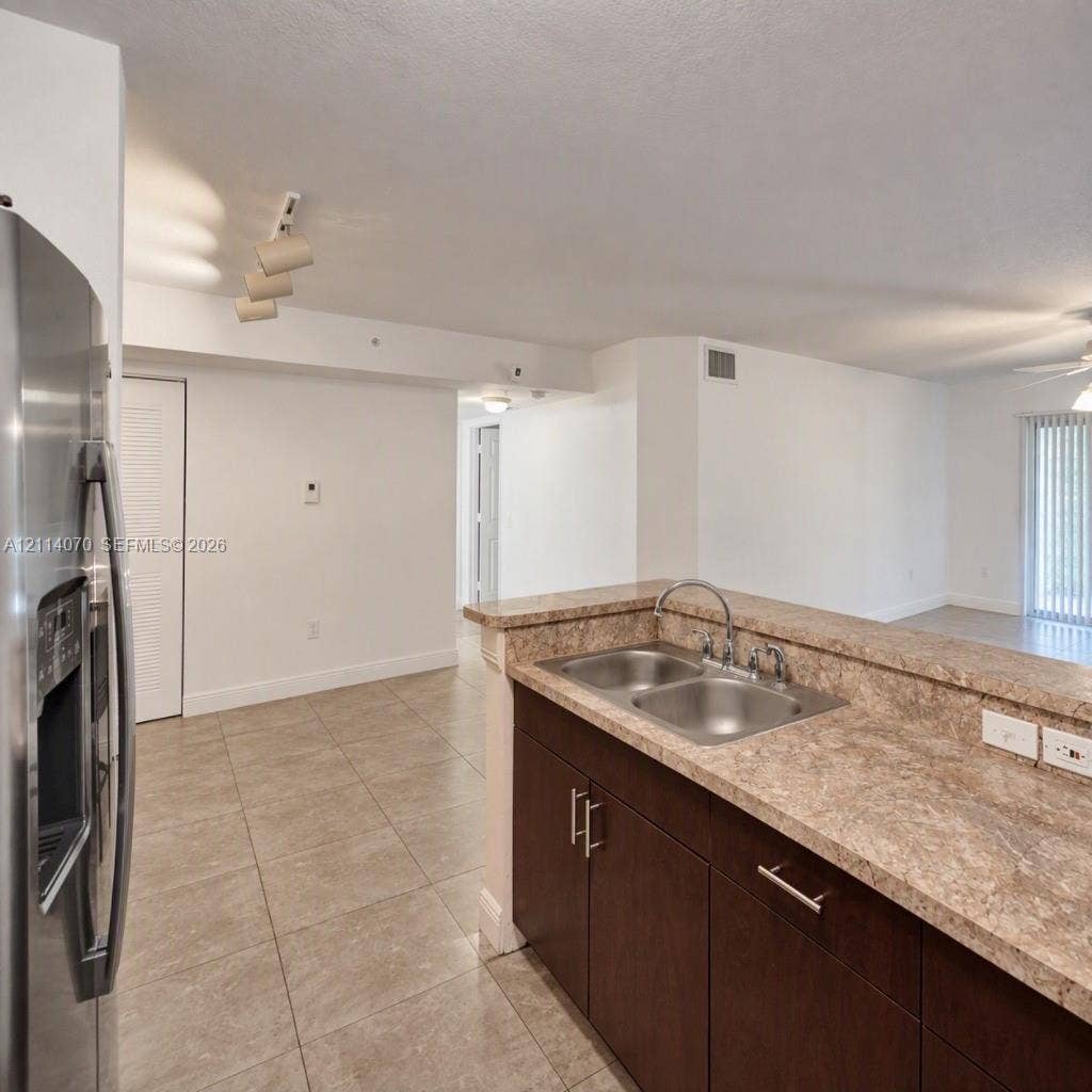 15400 SW 284th Street, #1204, Homestead, Homestead, FL 33033 Kitchen featuring dark wood-finish cabinetry, stone-texture countertops, stainless steel dual-basin sink, and tile flooring