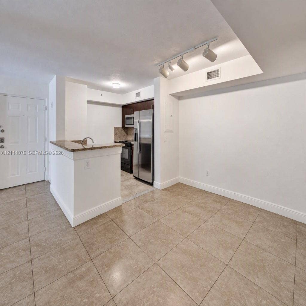 15400 SW 284th Street, #1204, Homestead, Homestead, FL 33033 Kitchen featuring stainless steel appliances, dark wood-finish cabinetry, stone-surfaced breakfast bar, and tile flooring throughout
