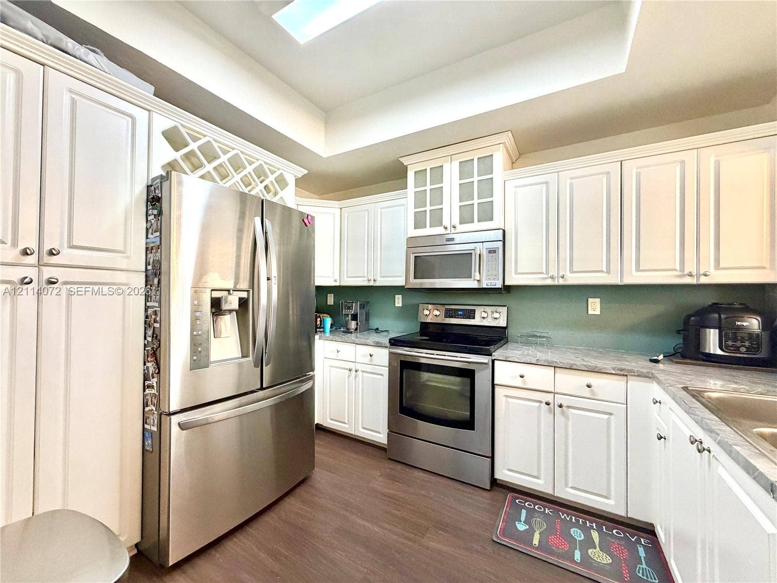 8964 W Flagler Street, #107, Miami, Miami, FL 33174 Kitchen featuring white cabinetry with integrated wine storage, stainless steel appliances, stone-finish countertops, and wood-finish flooring