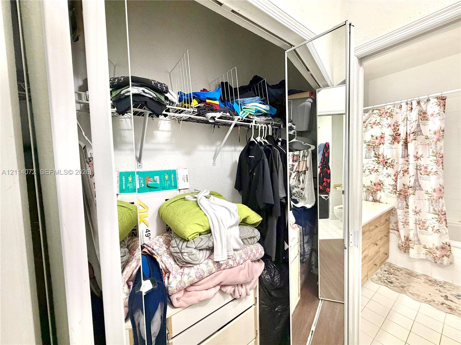 8964 W Flagler Street, #107, Miami, Miami, FL 33174 Closet featuring mirrored sliding doors and white wire shelving, accompanied by a bathroom vanity with wood-finish cabinetry