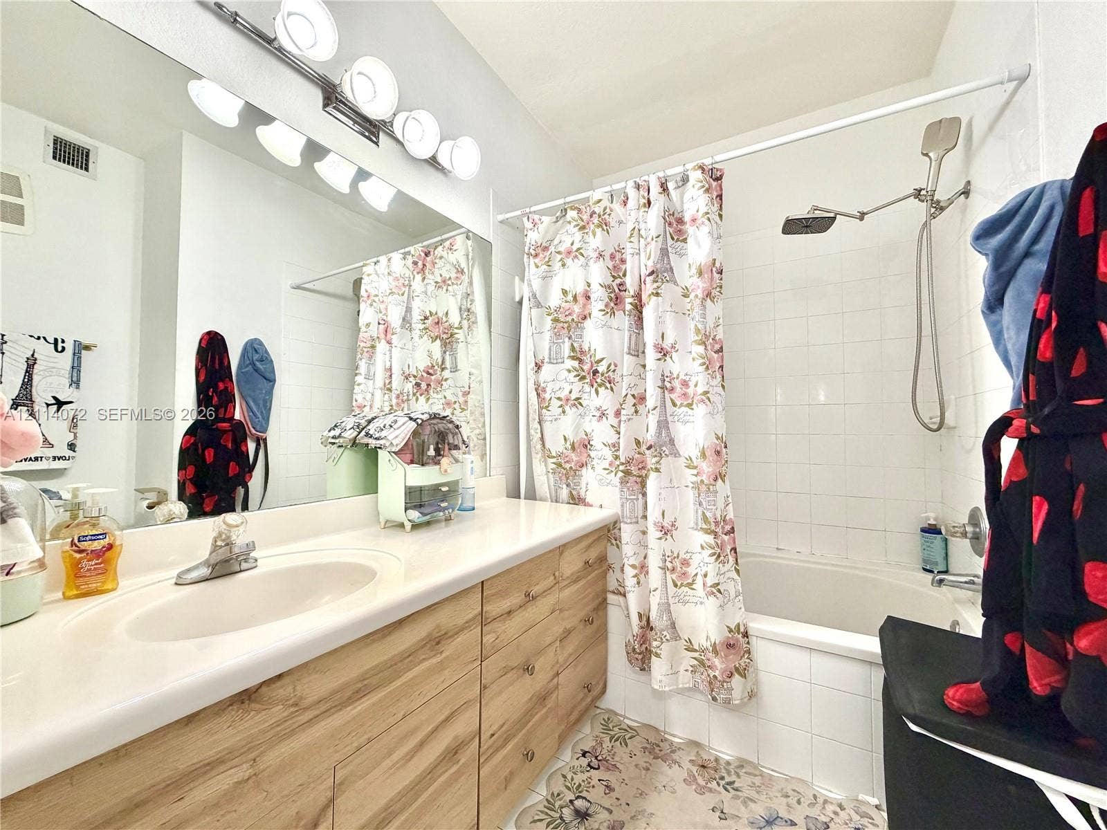 8964 W Flagler Street, #107, Miami, Miami, FL 33174 Bathroom featuring a vanity with light wood-finish cabinetry, an integrated sink with a polished chrome faucet, a wall-to-wall mirror, multi-bulb lighting, and a shower-tub combination with white wall tile