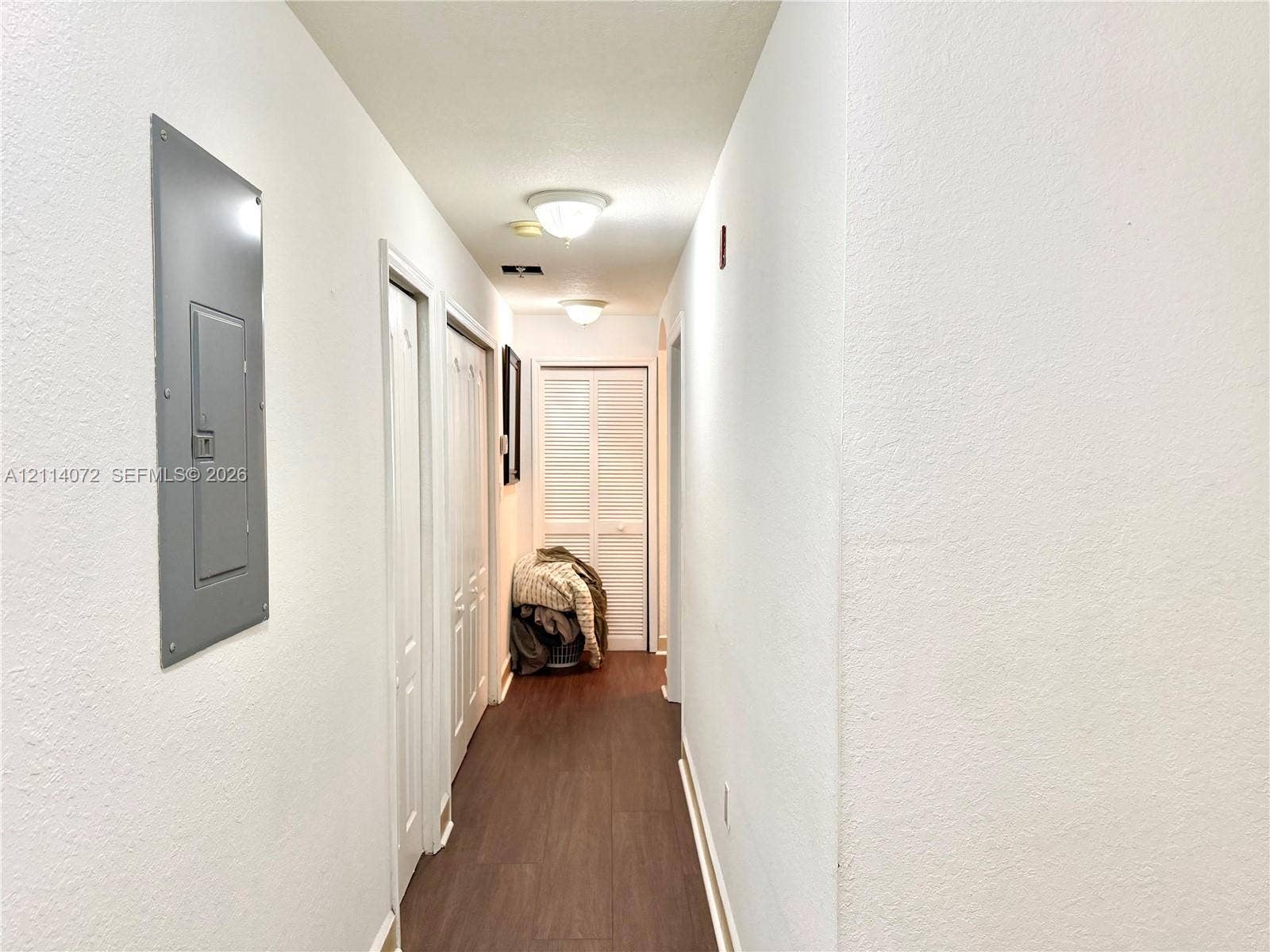 8964 W Flagler Street, #107, Miami, Miami, FL 33174 Interior hallway featuring wood-finish flooring, two sets of louvered closet doors, and flush-mount ceiling lighting