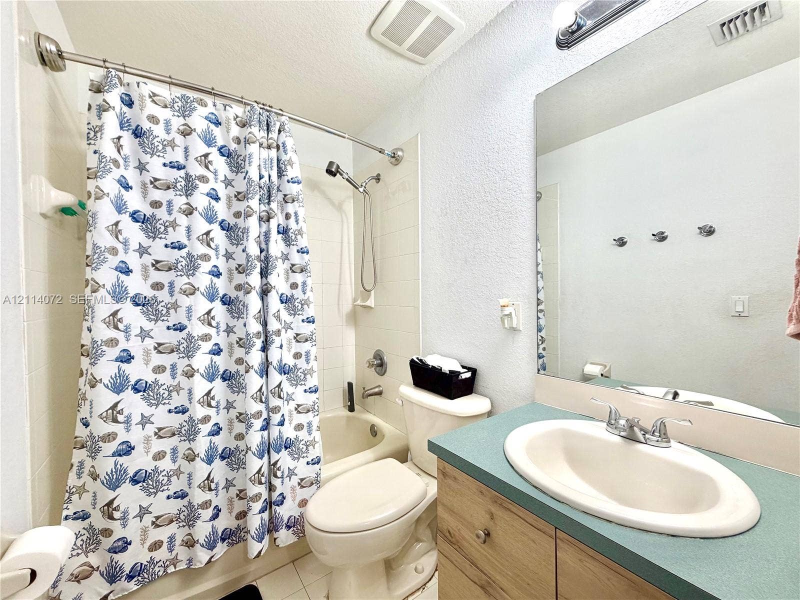 8964 W Flagler Street, #107, Miami, Miami, FL 33174 Bathroom featuring a wood-finish vanity cabinet, solid-surface countertop with an integrated oval sink, and a full-width vanity mirror