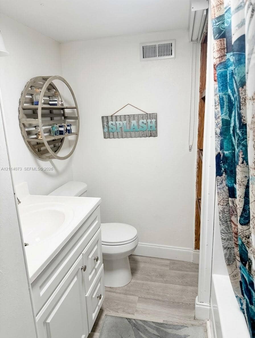 Bathroom featuring a white vanity cabinet with a integrated sink, wood-finish flooring, and a tub-shower combination