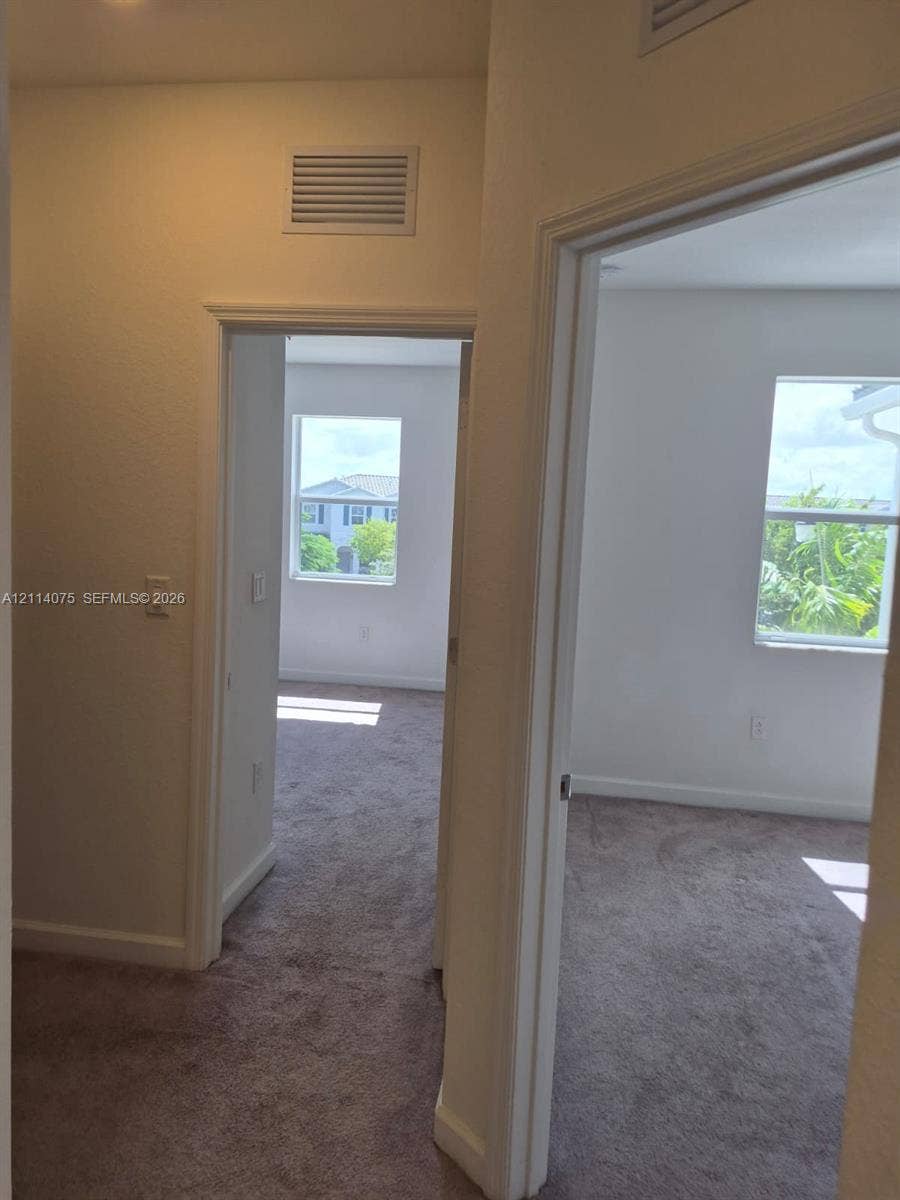 2659 SE 11th Street, Homestead, FL 33035 Neutral-toned carpeted flooring, white interior walls, and multiple single-hung windows providing natural light