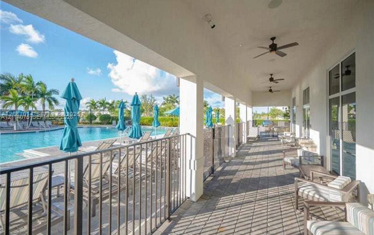 2659 SE 11th Street, Homestead, FL 33035 Covered patio featuring paver flooring, multiple ceiling fans, and a metal perimeter fence overlooking a swimming pool