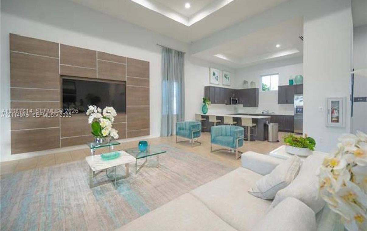2659 SE 11th Street, Homestead, FL 33035 Tray ceiling with recessed lighting, custom wood-finish media wall, large-format tile flooring, kitchen island with bar seating, and dark-toned cabinetry