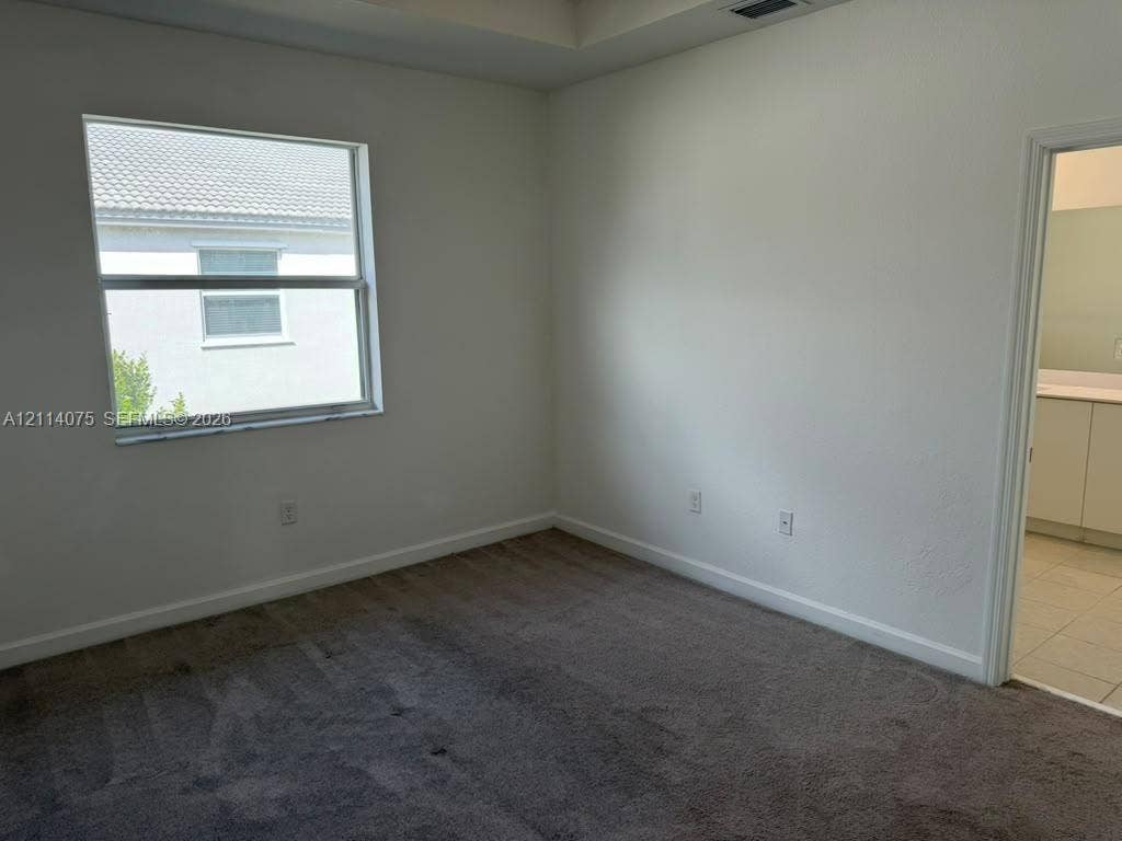 2659 SE 11th Street, Homestead, FL 33035 Interior space featuring neutral-toned carpeting, a tray ceiling, and a single-pane window