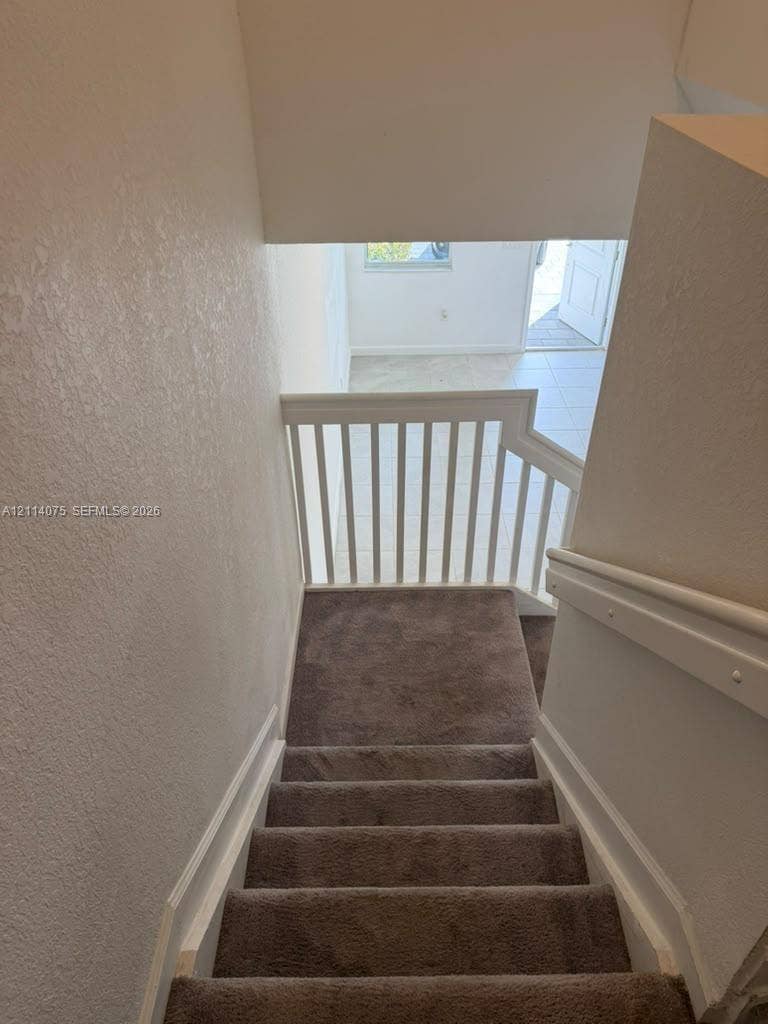 2659 SE 11th Street, Homestead, FL 33035 Staircase featuring wall-to-wall carpeting, a white wood railing, and painted walls