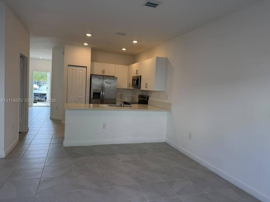 2659 SE 11th Street, Homestead, FL 33035 Kitchen featuring white cabinetry, solid-surface countertops, recessed lighting, tile flooring, and stainless steel appliances