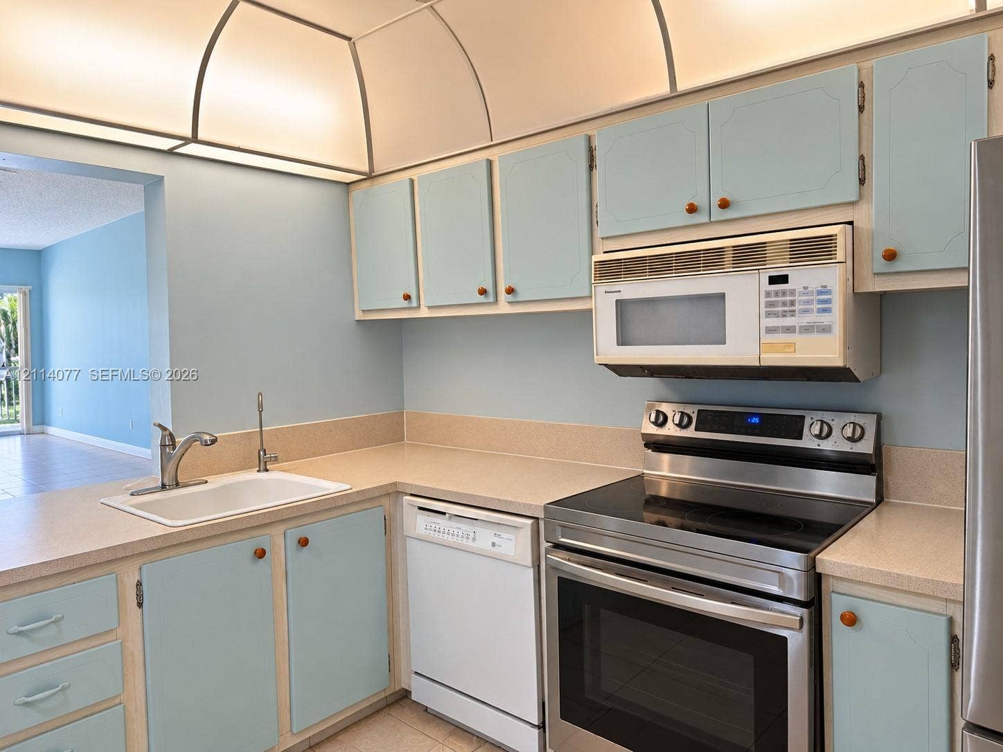 465 Paradise Isle Boulevard, #206, Hallandale Beach, Hallandale Beach, FL 33009 Kitchen featuring built-in cabinetry, solid-surface countertops, integrated cove lighting, and stainless steel appliances