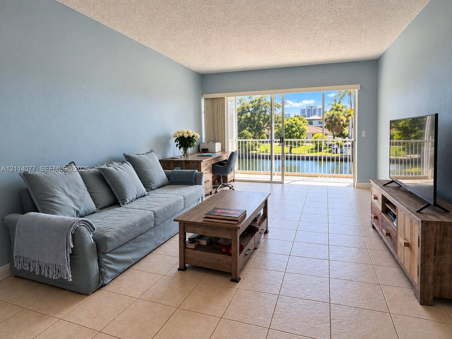 465 Paradise Isle Boulevard, #206, Hallandale Beach, Hallandale Beach, FL 33009 Living space featuring oversized sliding glass doors, neutral tile flooring, and a balcony with water frontage