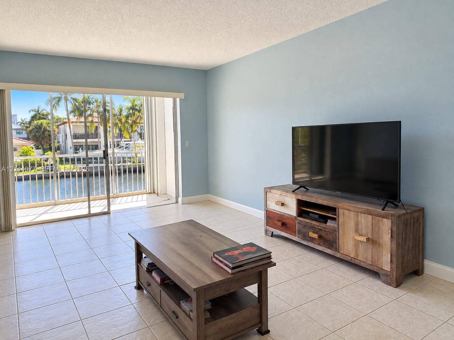 465 Paradise Isle Boulevard, #206, Hallandale Beach, Hallandale Beach, FL 33009 Sliding glass doors opening to a balcony with metal railings, tile flooring, and water frontage