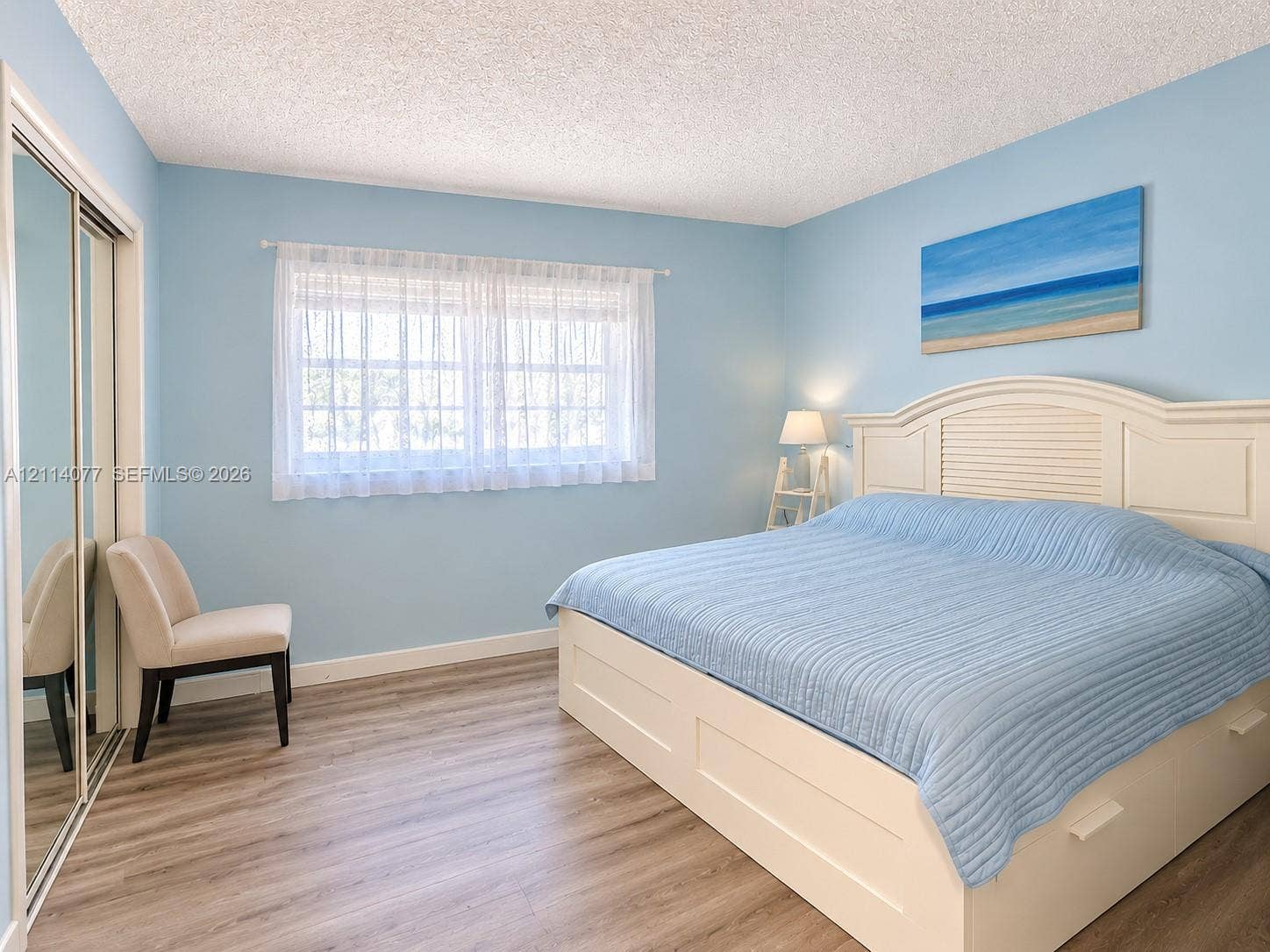 465 Paradise Isle Boulevard, #206, Hallandale Beach, Hallandale Beach, FL 33009 Room featuring wood-finish flooring, sliding mirrored closet doors, and a window with a sheer curtain treatment