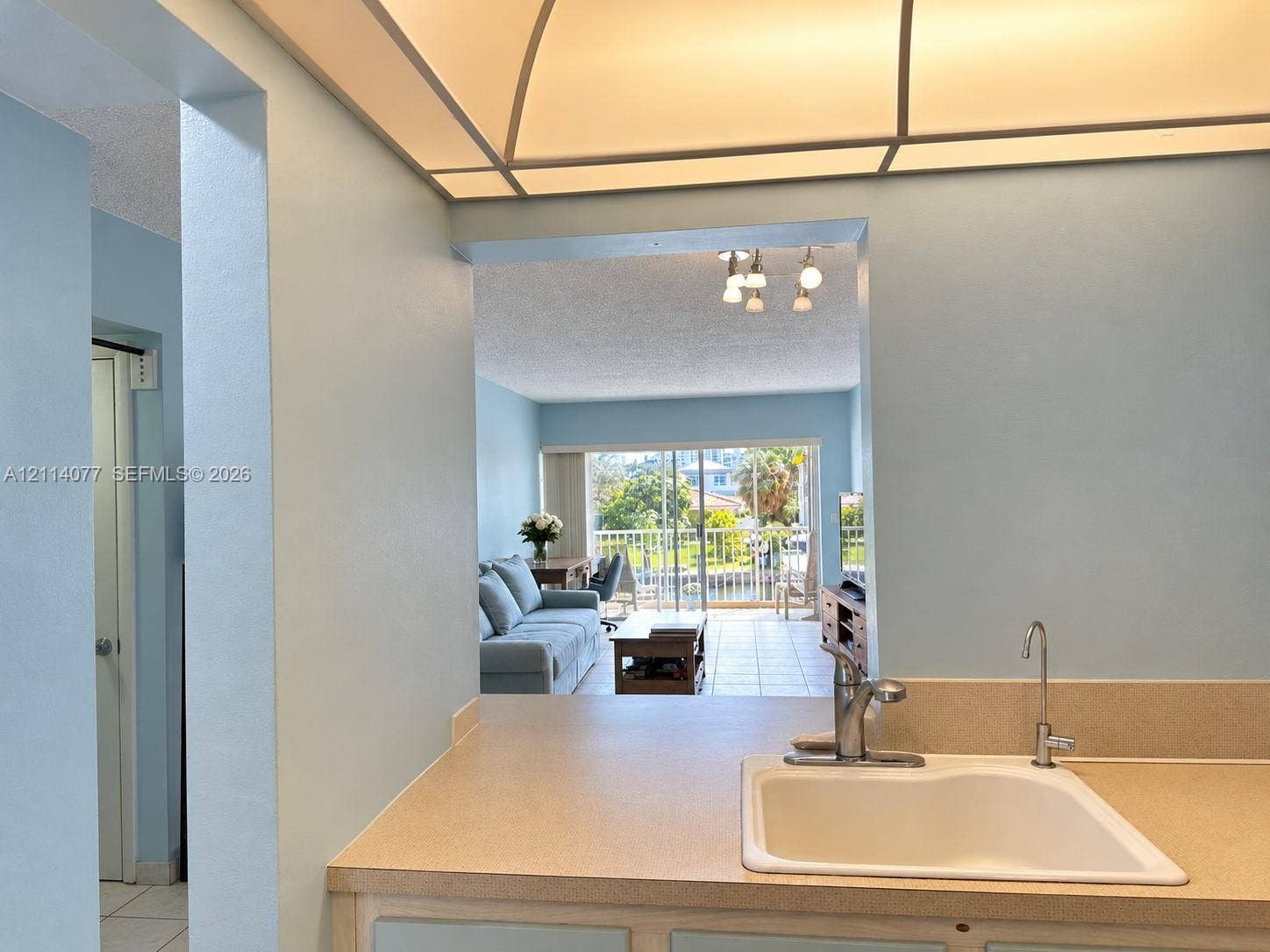 465 Paradise Isle Boulevard, #206, Hallandale Beach, Hallandale Beach, FL 33009 Kitchen featuring solid-surface countertops, integrated sink, and gooseneck faucet beneath a recessed tray ceiling with integrated lighting