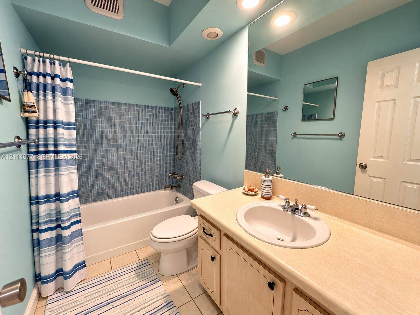 465 Paradise Isle Boulevard, #206, Hallandale Beach, Hallandale Beach, FL 33009 Bathroom featuring a bathtub with blue mosaic tile surround, built-in vanity with a solid surface countertop, integrated oval sink, and large wall-mounted mirror