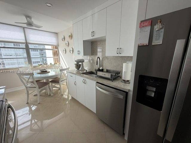 Kitchen featuring white cabinetry, stone-finish countertops, stainless steel appliances, and large-format tile flooring