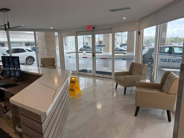 Reception area featuring polished tile flooring, floor-to-ceiling glass panel walls, and a multi-tiered counter with a stone-finish surface