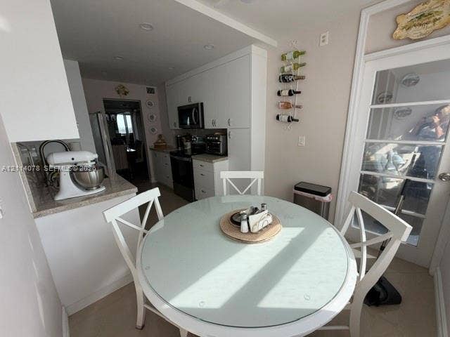 Kitchen featuring white shaker-style cabinetry, solid-surface countertops, recessed lighting, and a multi-lite door with glass inserts