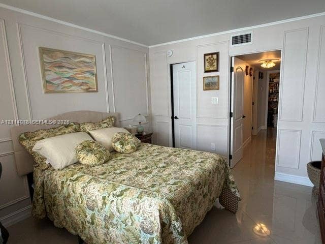 Interior space featuring walls with applied wainscoting trim, polished stone-finish tile flooring, and solid-core interior doors with arched-top detailing