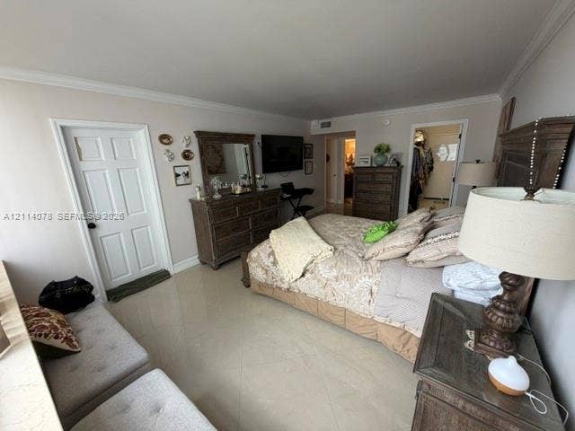 Neutral-toned room featuring large-format tile flooring, crown molding, a multi-panel interior door, and overhead lighting