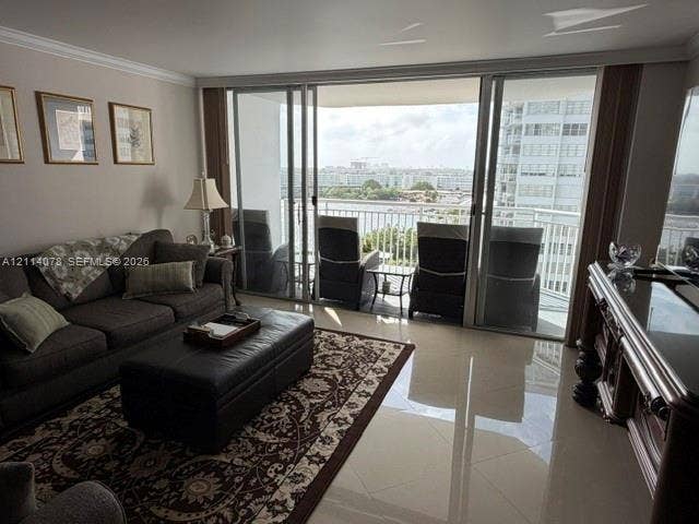 Large sliding glass doors opening to a covered balcony, polished tile flooring, and crown molding
