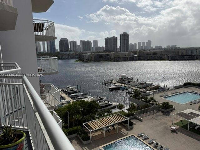 Private balcony with white metal railings, overlooking a waterfront marina, swimming pools, and paved sun deck