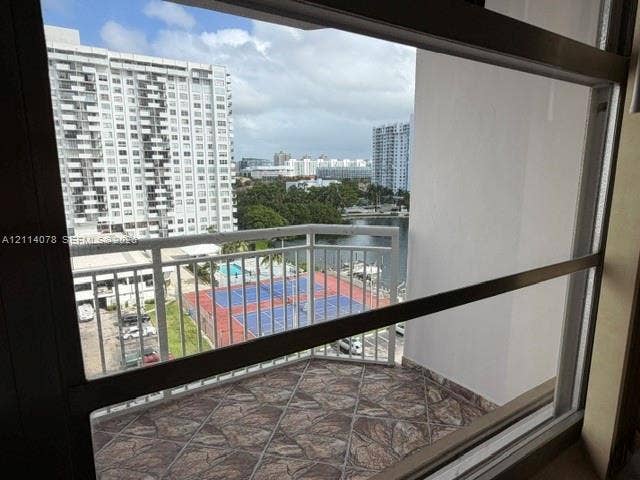 Private balcony featuring flagstone-style tiling and a white metal railing