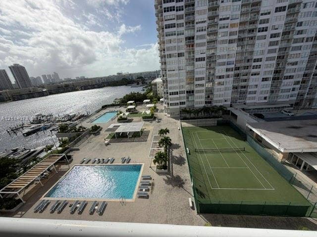 Outdoor amenities featuring multiple swimming pools, a tennis court, shaded seating structures, and a private dock area