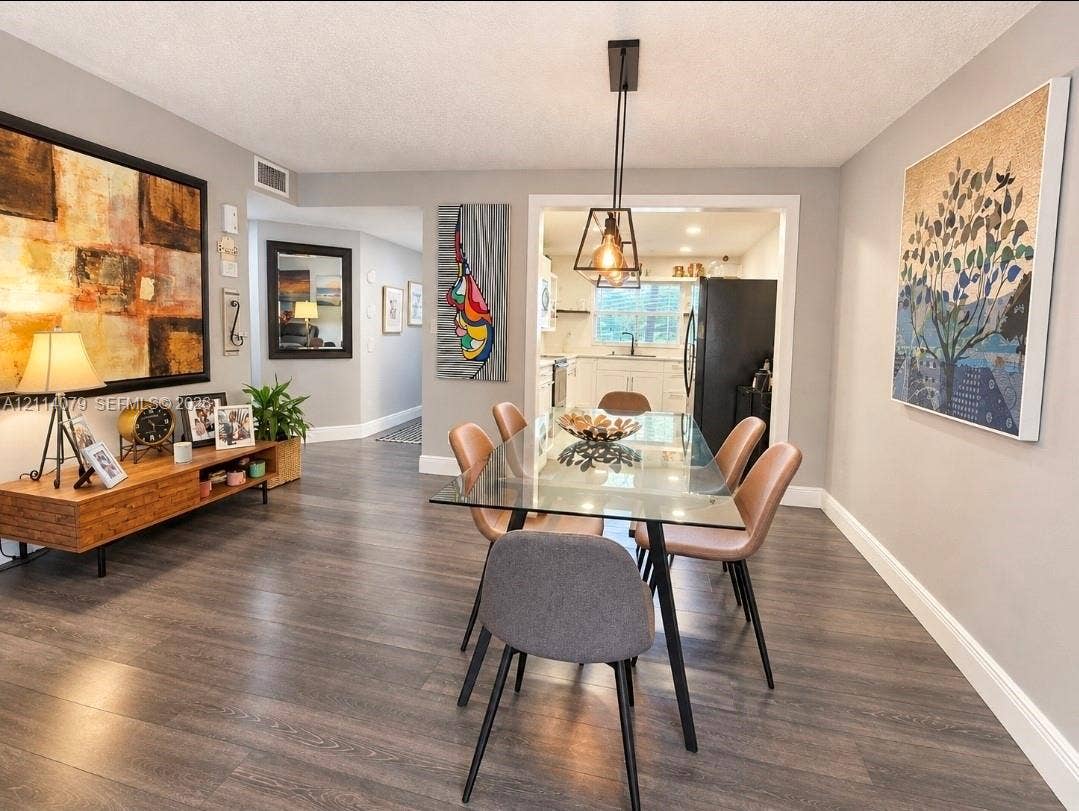 9241 Sunrise Lakes Boulevard, #109, Sunrise, FL 33322 Dining area featuring wood-finish flooring, a geometric pendant light fixture, and neutral wall tones