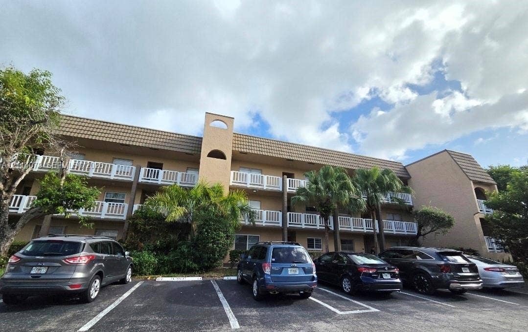 9241 Sunrise Lakes Boulevard, #109, Sunrise, FL 33322 Multi-story building exterior featuring a textured stucco facade, Mansard-style roofline, and white balcony railings