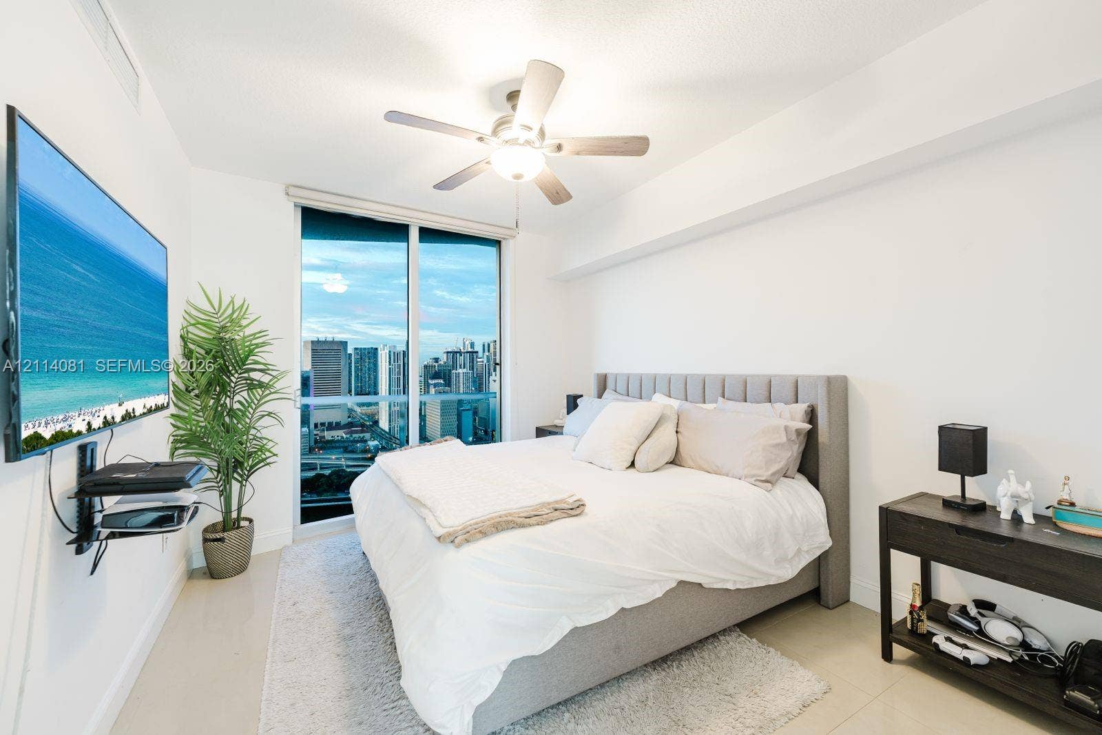 185 SW 7th Street, #3609, Miami, Miami, FL 33130 Floor-to-ceiling glass sliding doors, neutral tile flooring, and a ceiling-mounted light fixture with integrated fan