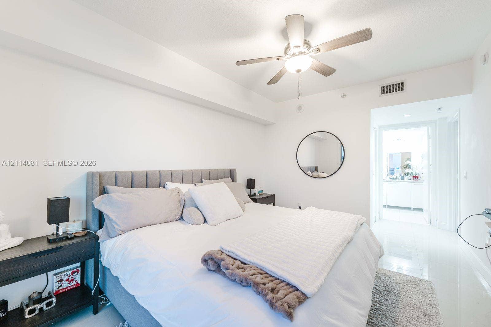 185 SW 7th Street, #3609, Miami, Miami, FL 33130 Neutral-toned room featuring high-gloss flooring, a ceiling fan with integrated lighting, and a circular wall-mounted mirror
