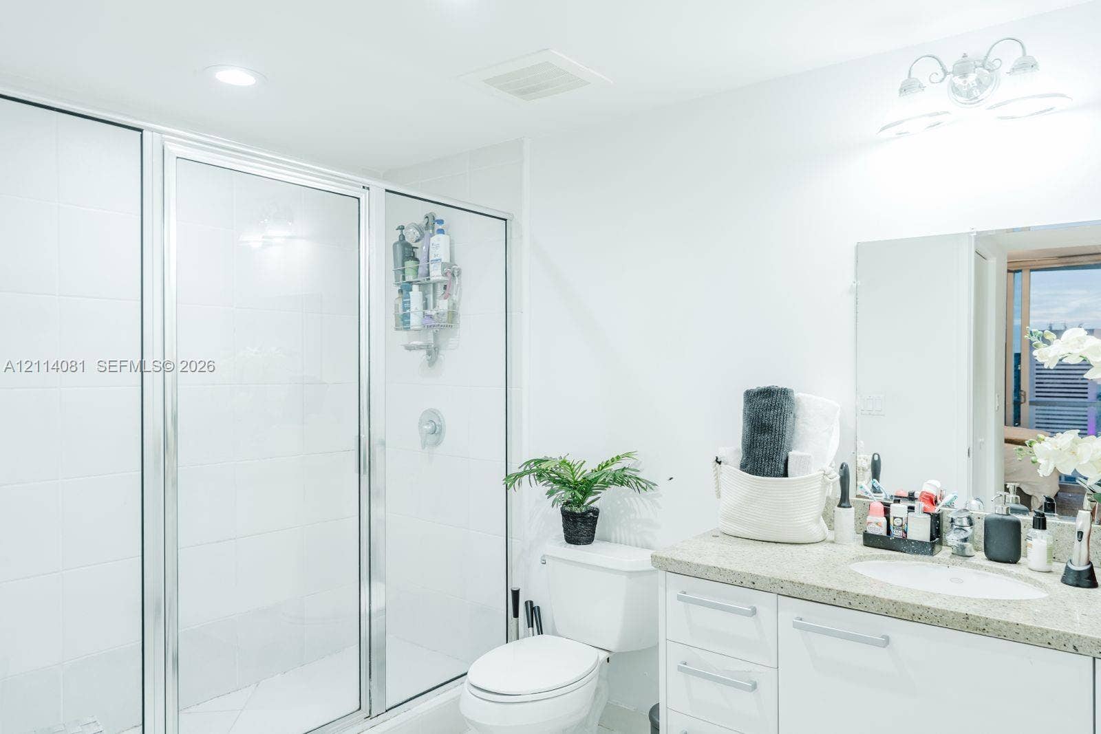 185 SW 7th Street, #3609, Miami, Miami, FL 33130 Bathroom featuring a glass-enclosed shower with white wall tile, a vanity with a stone-finish countertop and an integrated sink, and an attached multi-bulb light fixture