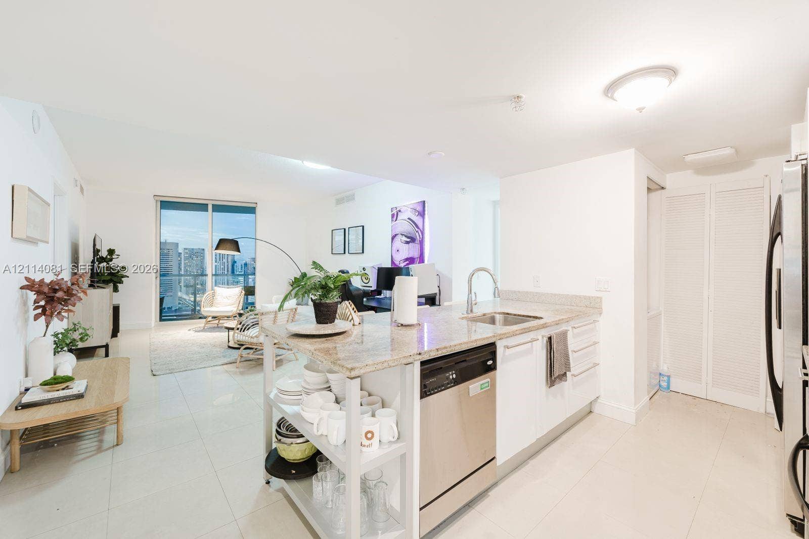 185 SW 7th Street, #3609, Miami, Miami, FL 33130 Kitchen featuring a stone-surface island, stainless steel dishwasher, integrated sink with a gooseneck faucet, white cabinetry, and light-tone tile flooring