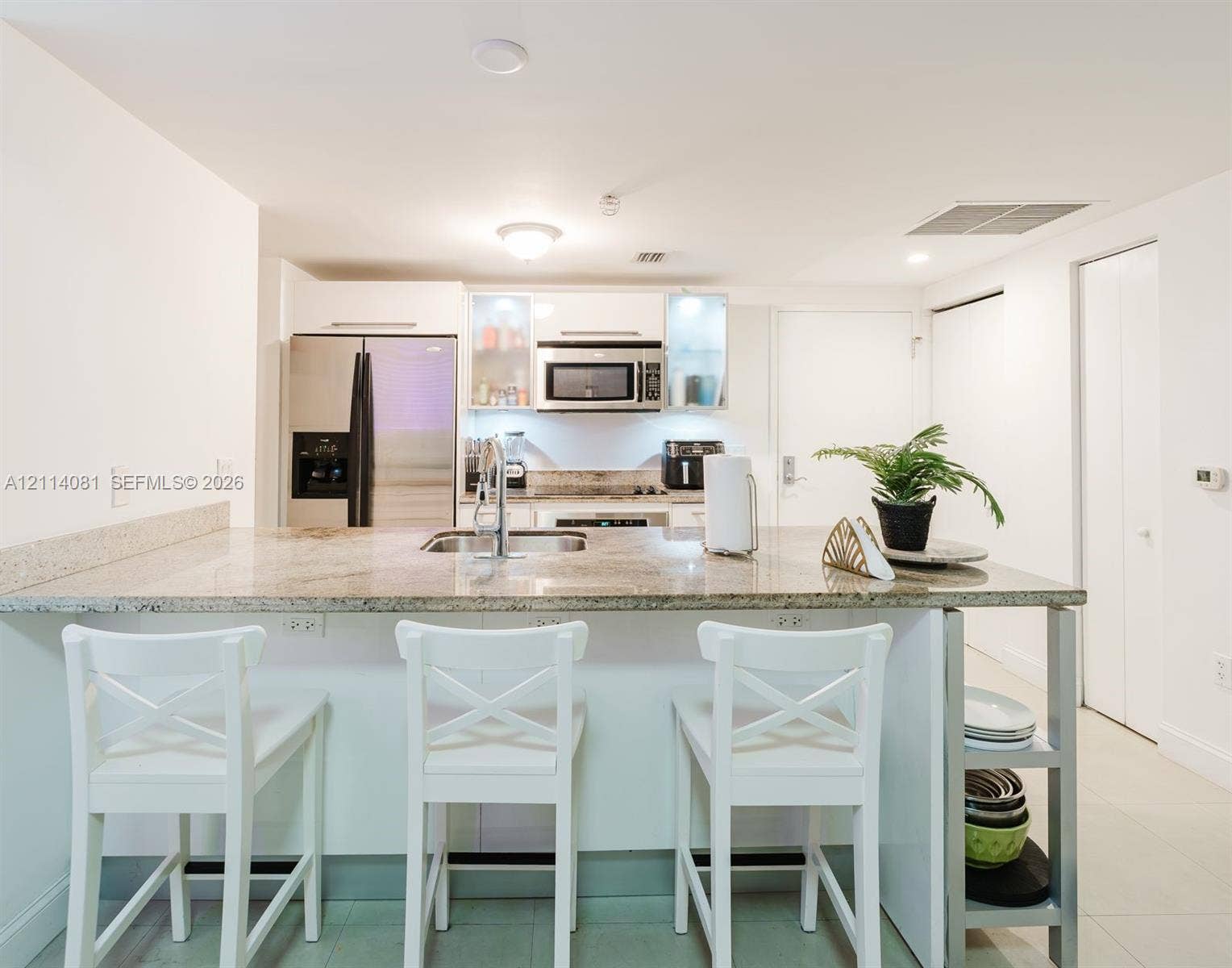 185 SW 7th Street, #3609, Miami, Miami, FL 33130 Kitchen featuring a stone-topped island with an integrated stainless steel sink, flat-panel white cabinetry, built-in stainless steel microwave, and stainless steel refrigerator
