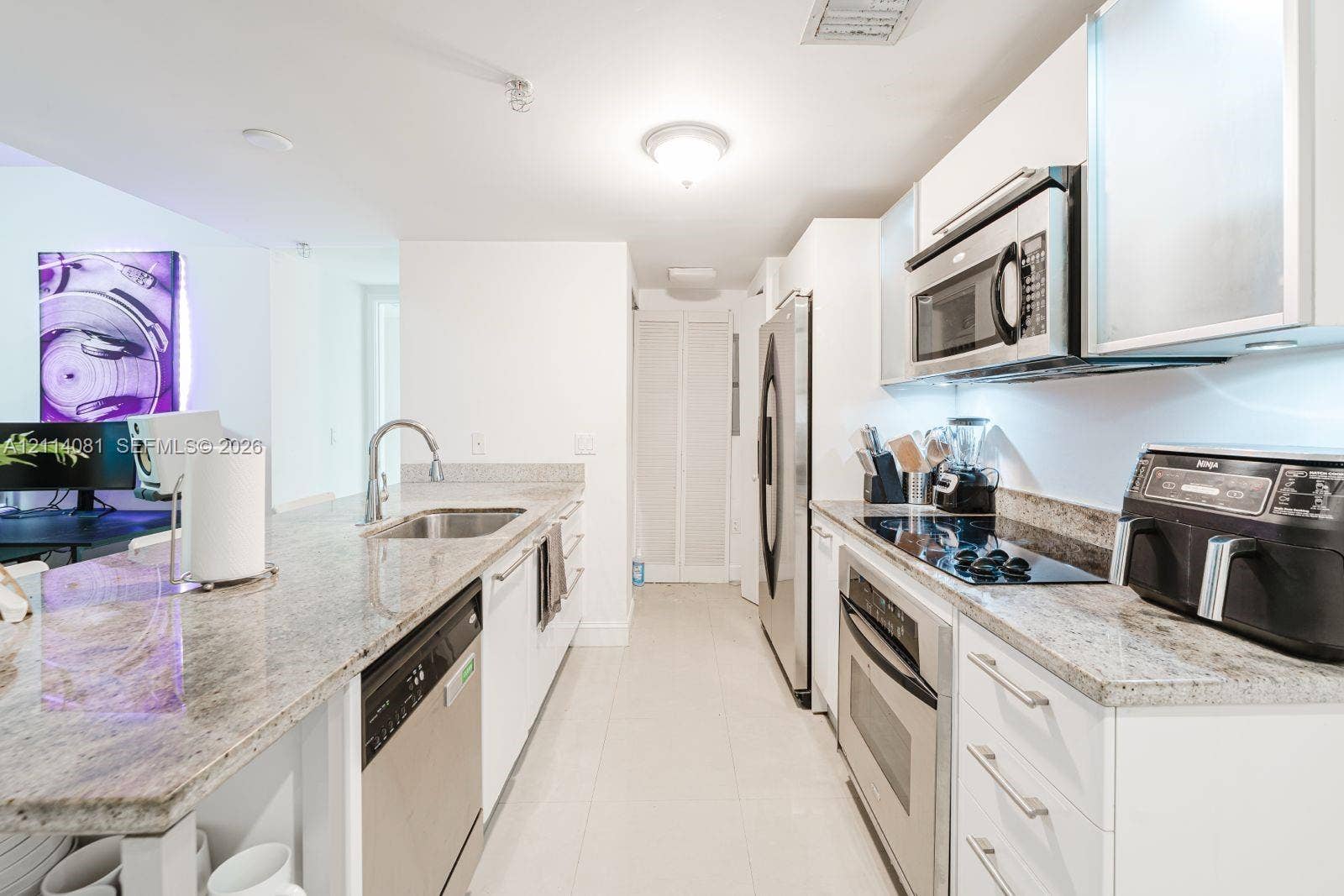 185 SW 7th Street, #3609, Miami, Miami, FL 33130 Kitchen featuring stone countertops, white cabinetry, integrated stainless steel appliances, and tile flooring