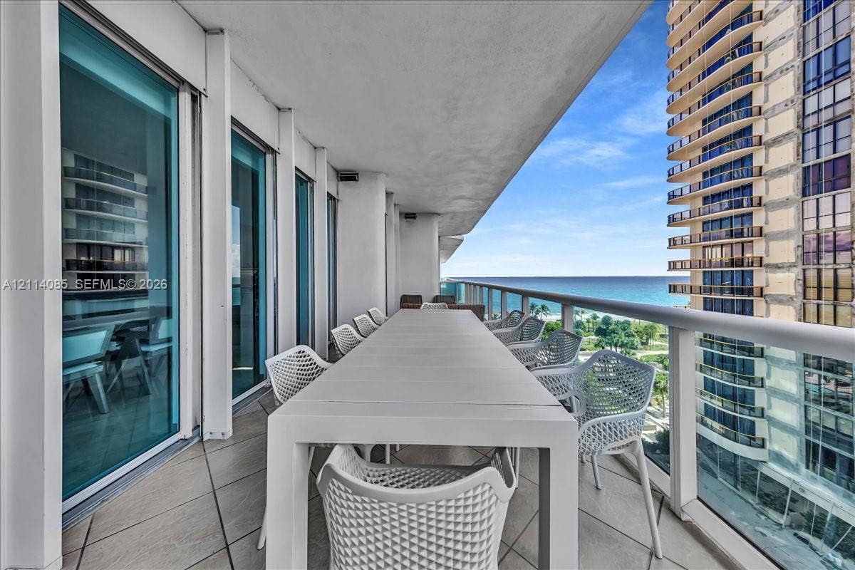10101 Collins Avenue, #8D, Bal Harbour, FL 33154 Spacious covered balcony featuring large-format tile flooring, floor-to-ceiling glass panels, and a metal railing