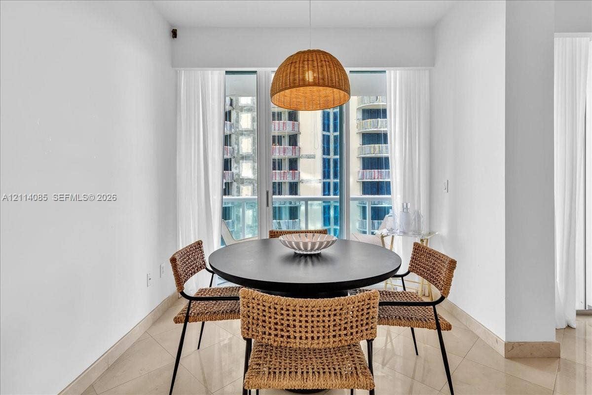 10101 Collins Avenue, #8D, Bal Harbour, FL 33154 Floor-to-ceiling glass sliding doors, stone-finish flooring, and a textured pendant light fixture