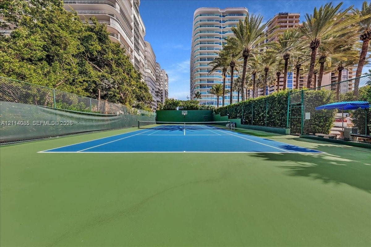10101 Collins Avenue, #8D, Bal Harbour, FL 33154 Private tennis court featuring a hard-surface surface, chain-link perimeter fencing, and mature perimeter landscaping